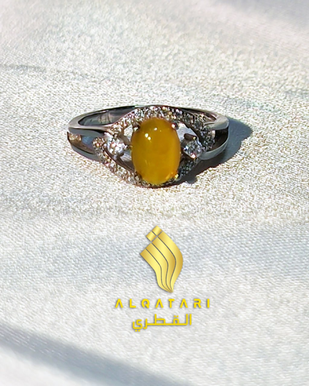 Top view of silver ring with oval yellow agate and zircon halo on satin background