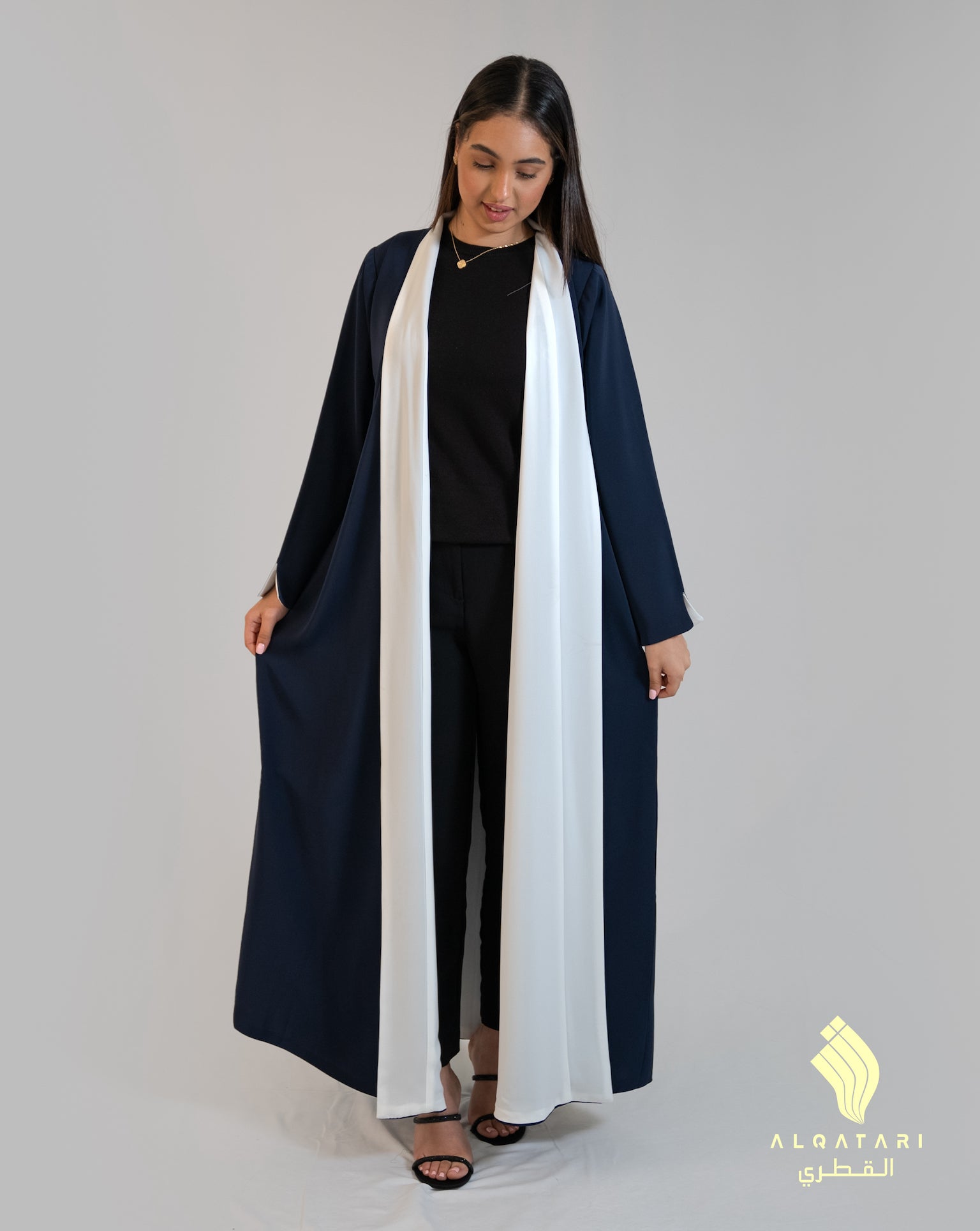 Model wearing a navy and white two-toned reversible abaya from Al Qatari Gallery, styled open with the white panel at the front for a chic, layered look.