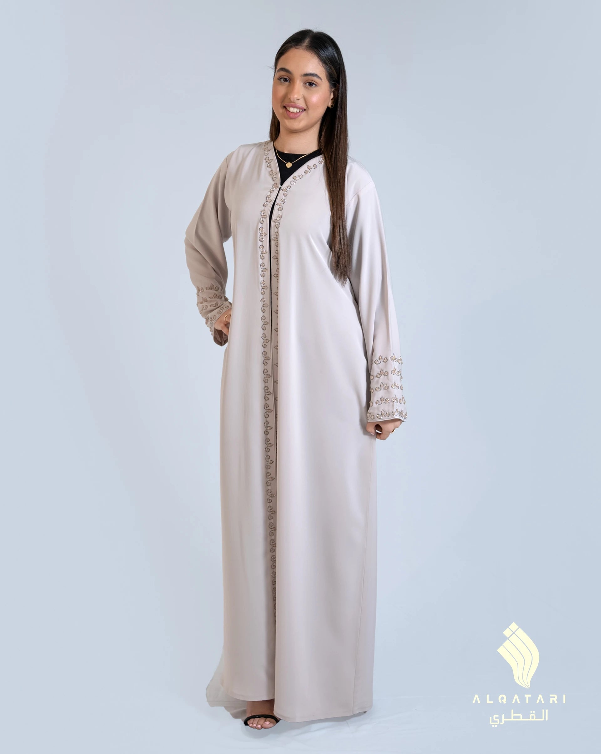 Model wearing a soft beige Mirage abaya with intricate hand embellishments on the front placket and sleeves, designed by AlQatari Gallery for elegant occasions.