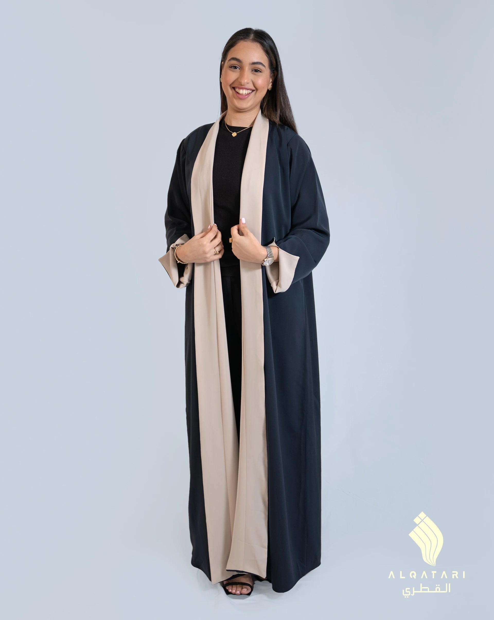 Model wearing the black and camel version of the reversible abaya from Al Qatari Gallery with inner camel panel and turned cuffs for contrast effect.