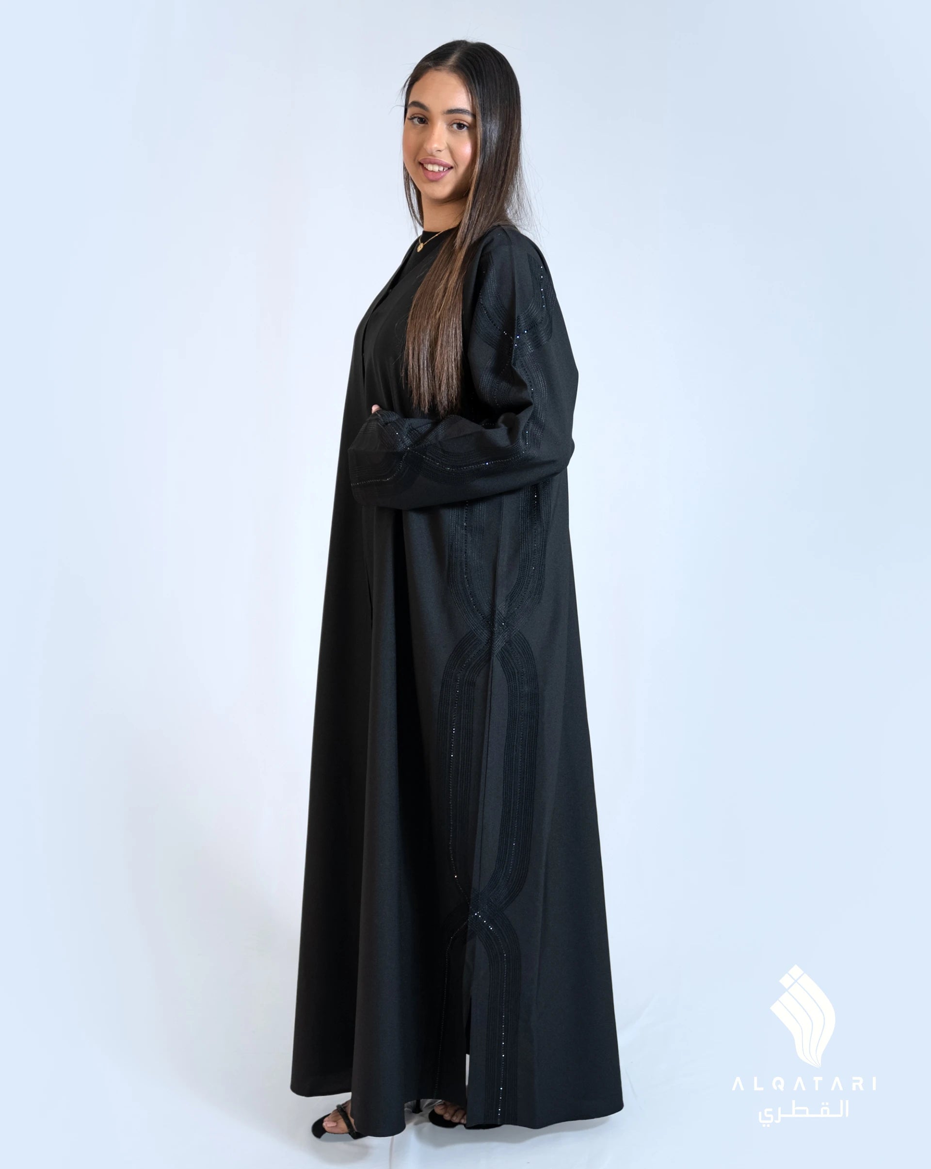 Model wearing a black abaya with subtle needlework on the sides and sleeves, adding delicate texture and elegance to the classic silhouette. Abaya from Al Qatari Gallery collection