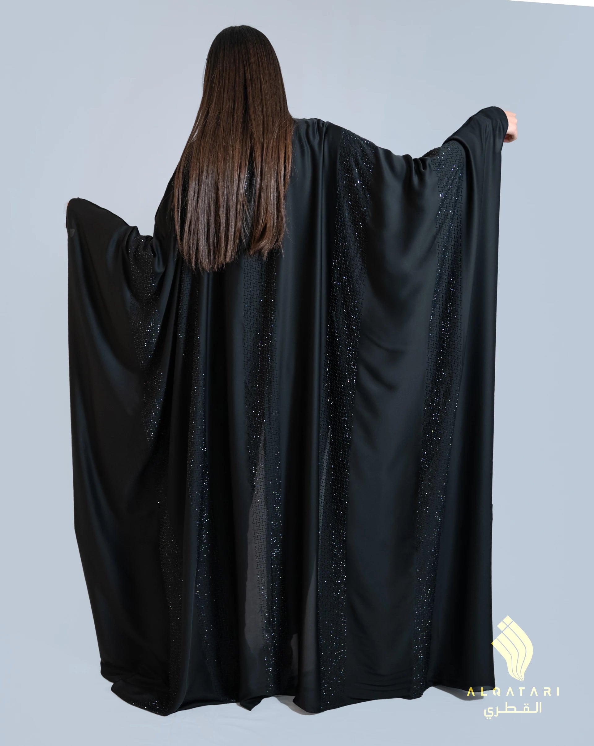 Back view of the Bahraini abaya from Al Qatari Gallery, revealing flowing satin panels adorned with linear beaded embellishments that shimmer with movement.
