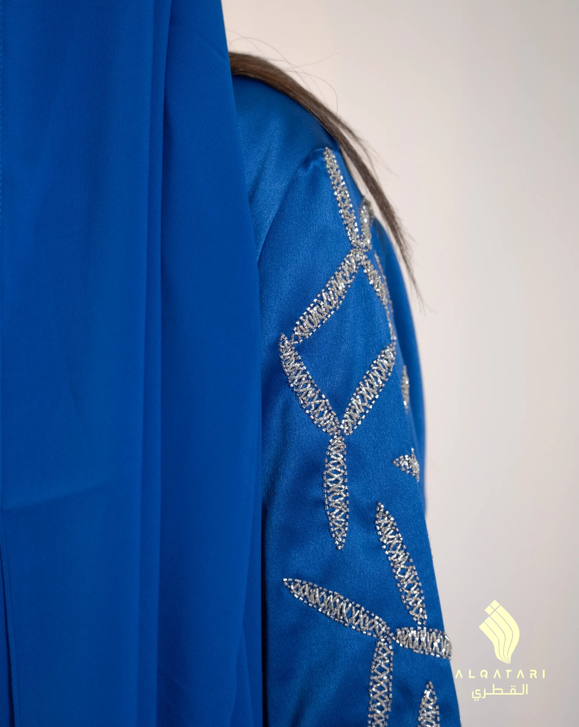 Close-up of a royal blue abaya sleeve with intricate silver embellishments in a geometric star pattern. The detailed beadwork reflects luxury craftsmanship from the Al Qatari Gallery collection.
