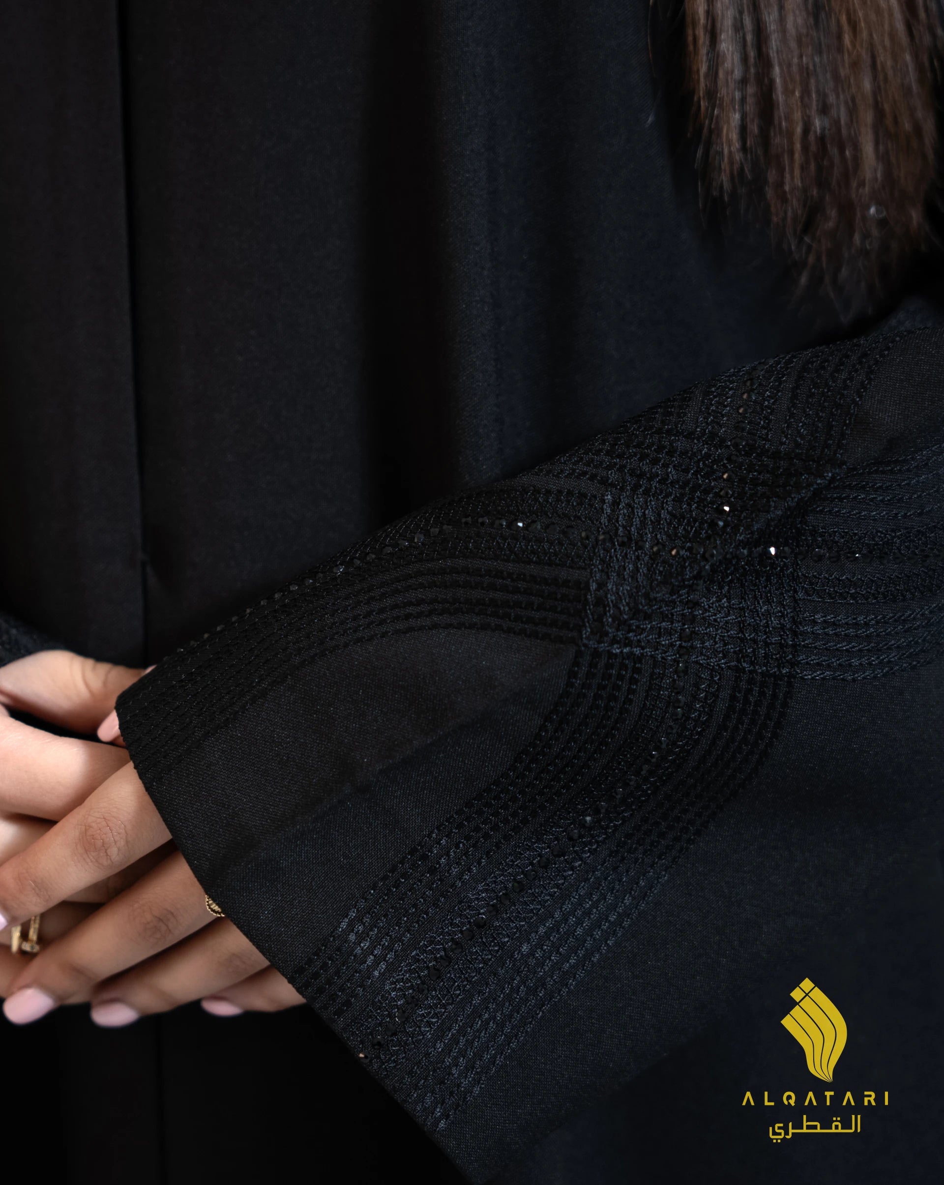 Close-up of the abaya sleeve showcasing intricate linear needlework patterns with a hint of shimmer on black Marina fabric. Abaya available on Al Qatari Gallery