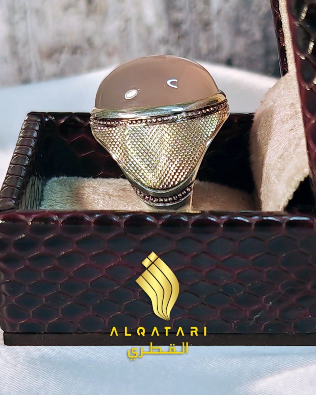 Front side view of Al Qatari men’s peach chalcedony ring in luxury textured box