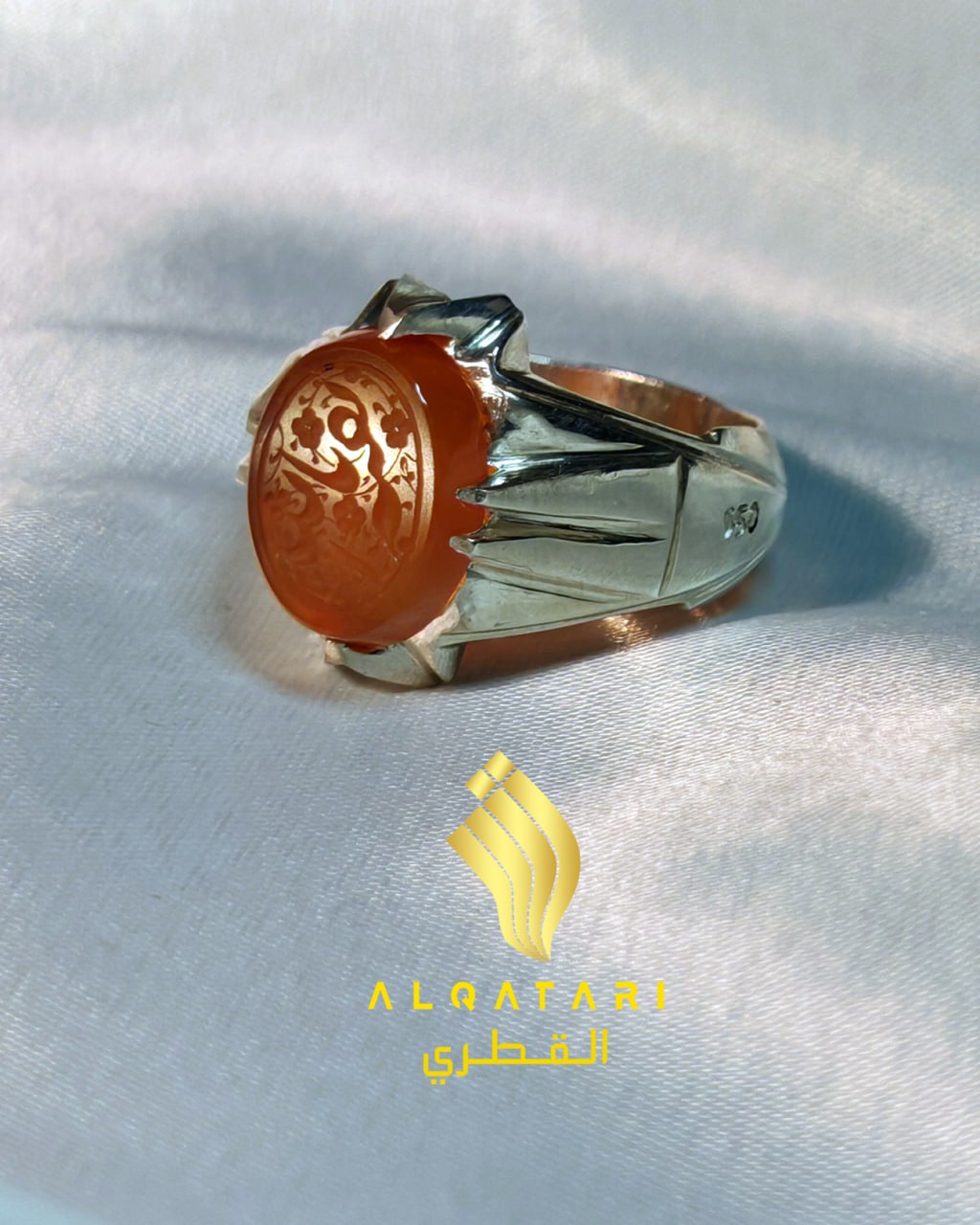 Side view of engraved orange agate ring in silver claw setting by Al Qatari on white satin