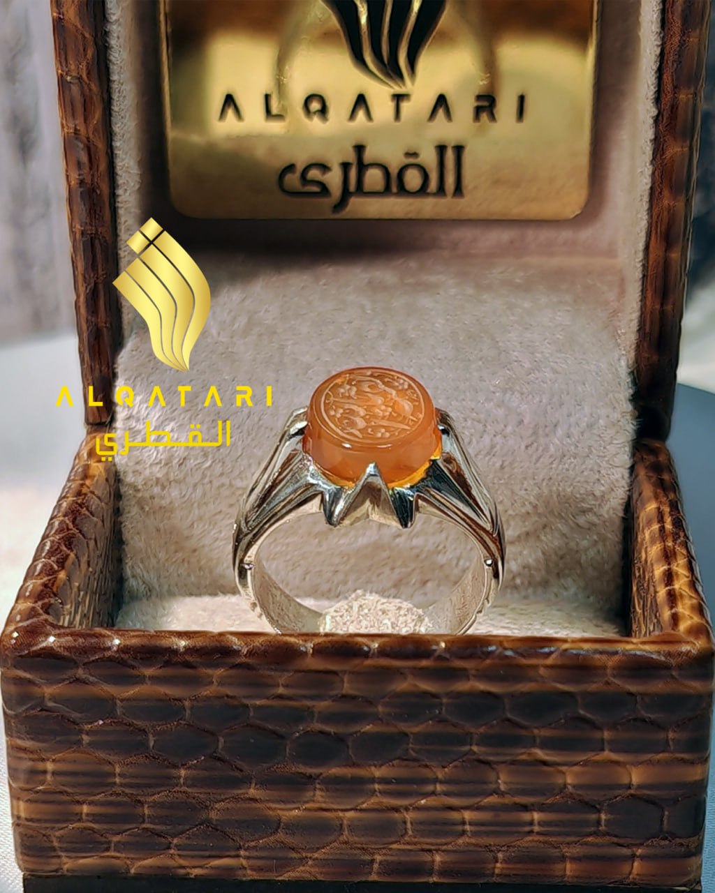 Frontal view of orange agate Islamic ring with Arabic script "Baqiyatullah", shown in velvet ring box