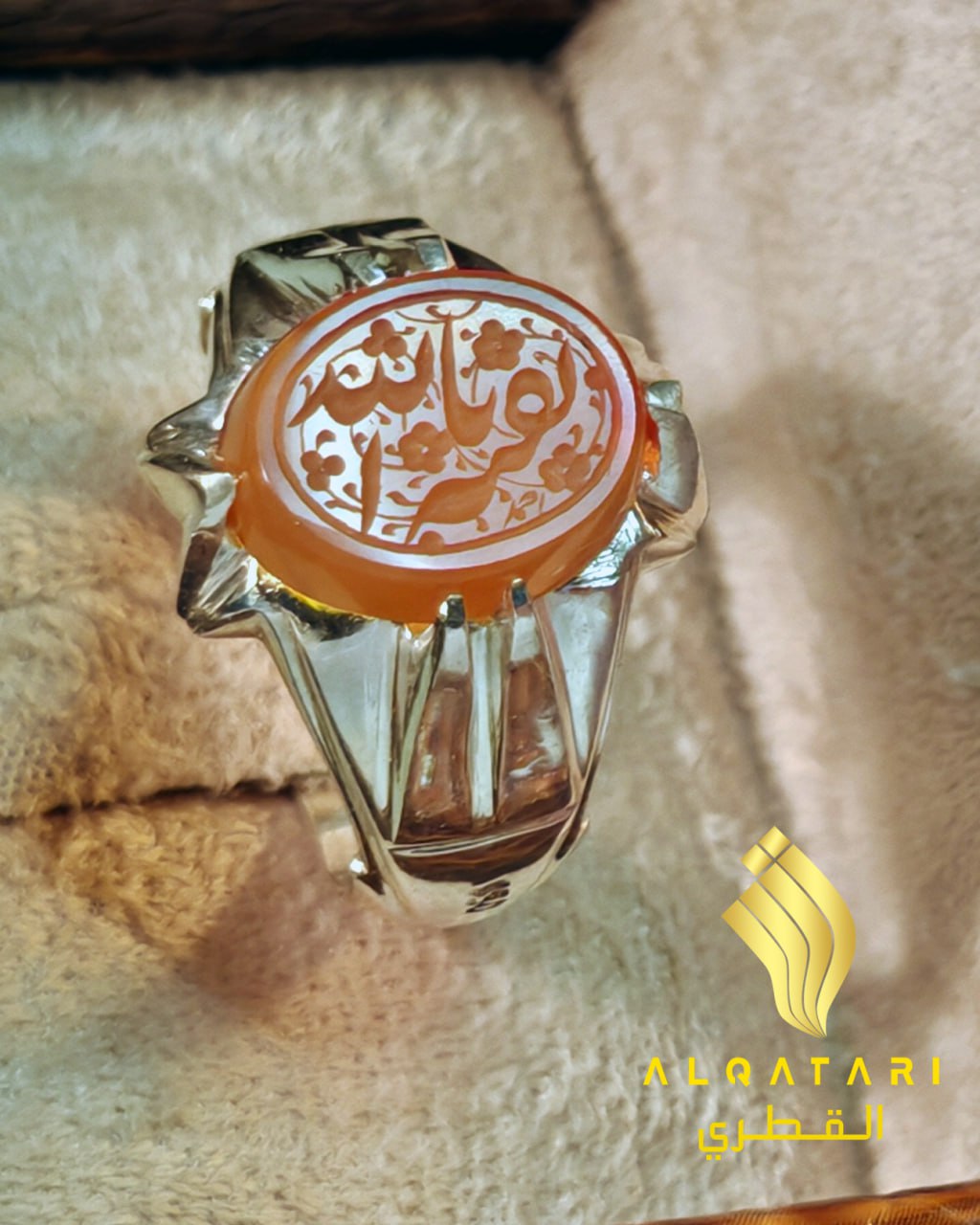 Top close-up of engraved orange aqeeq  gemstone ring with bold silver band in Al Qatari box