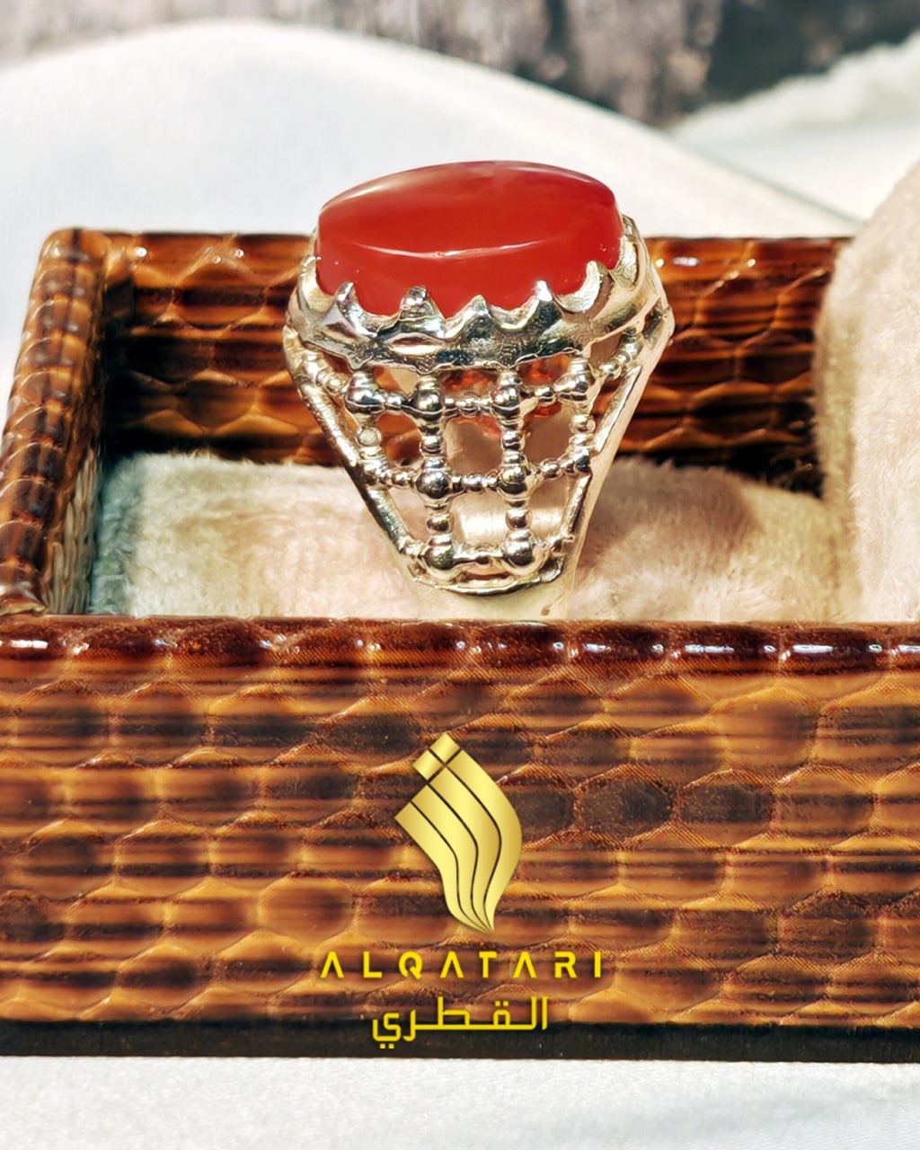 Frontal view of red aqeeq agate men’s ring with crown bezel and textured grid band in gift box