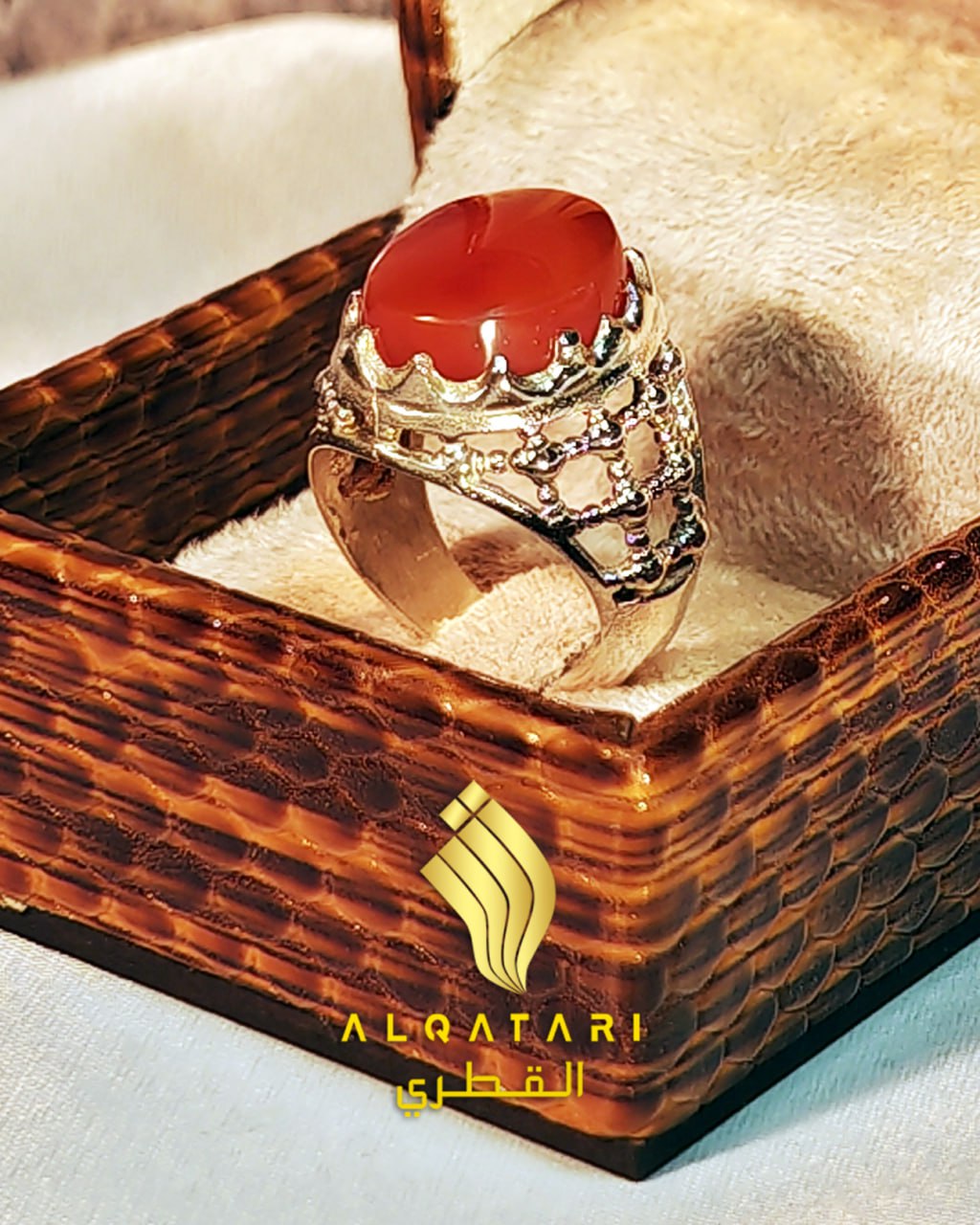 Angled close-up of red aqeeq Islamic ring with lattice silverwork in Al Qatari Gallery packaging