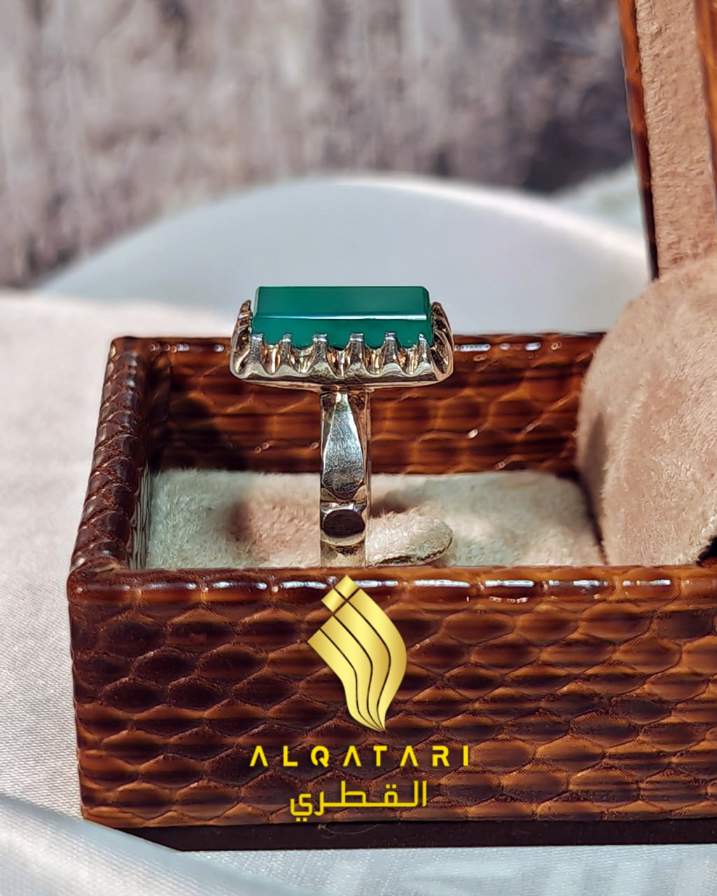 Side view of Al Qatari Gallery unisex silver ring with rectangular green agate stone in a luxury brown box