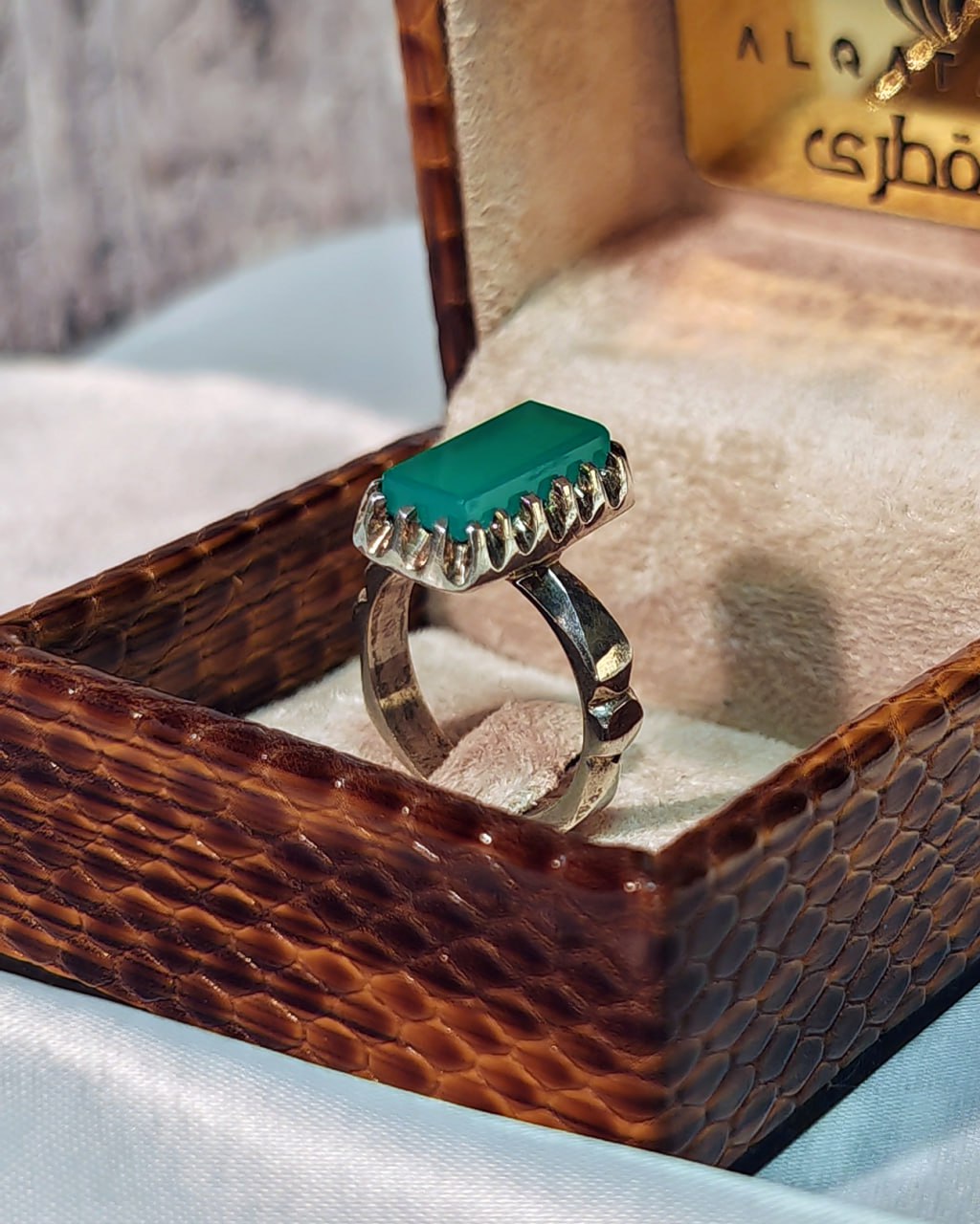 Angled side shot of Al Qatari silver men’s ring with bold green agate centerpiece, set in display box