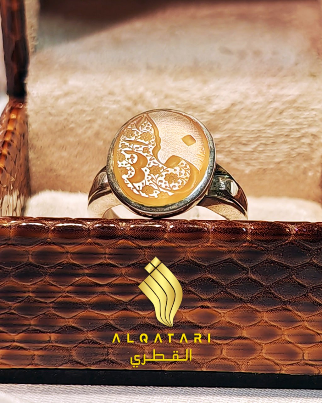 Front-facing view of amber agate Arabic calligraphy ring in a cushioned brown box