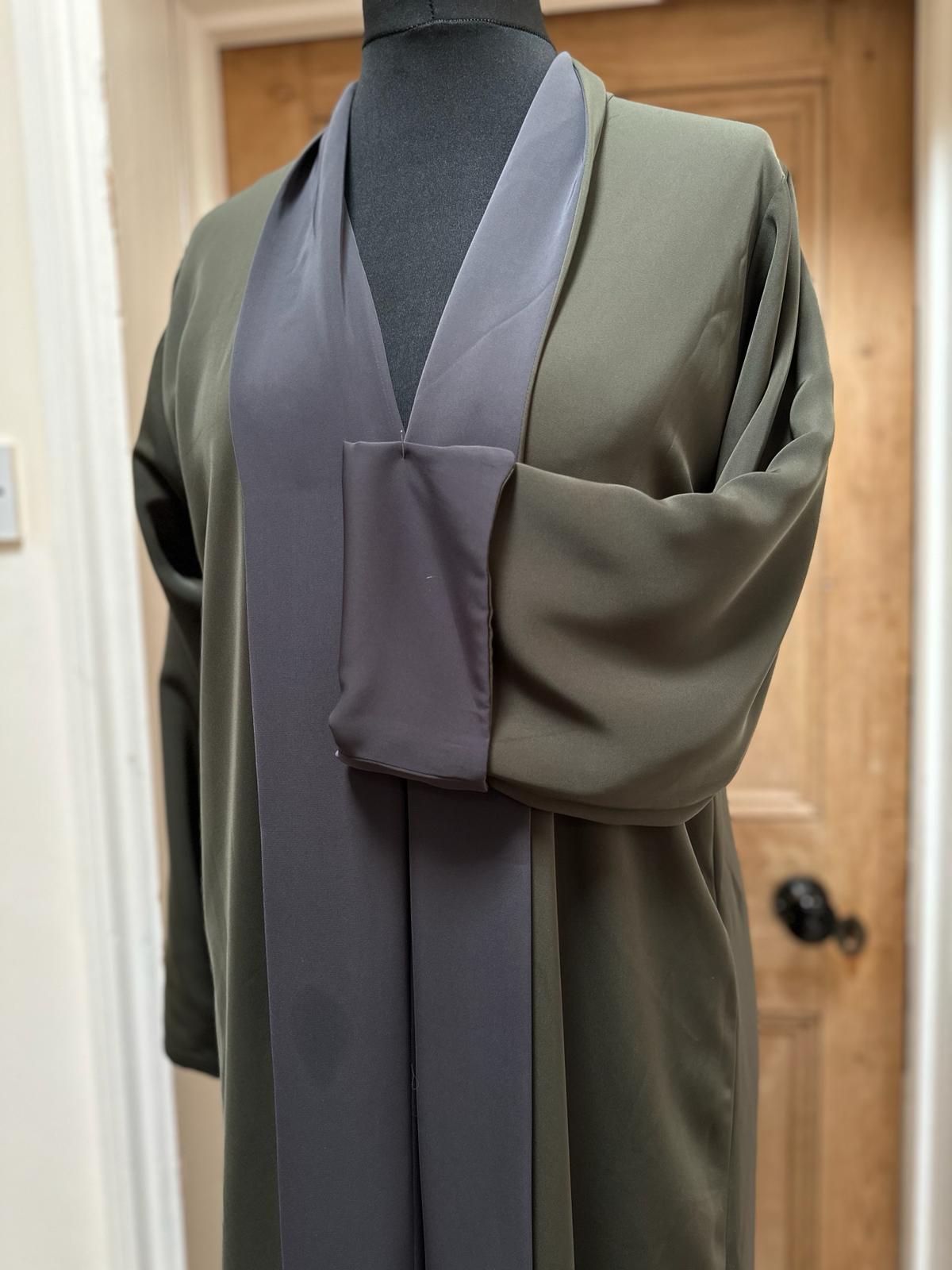 Khaki and grey abaya from Al Qatari Gallery on display, demonstrating structured collar and colour-block contrast.